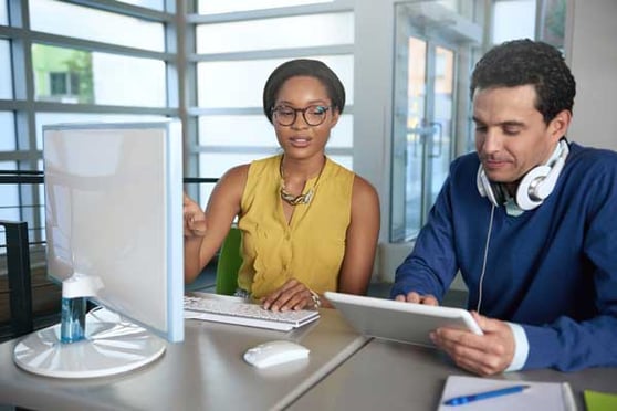 Two  colleages discussing ideas using a tablet and computer